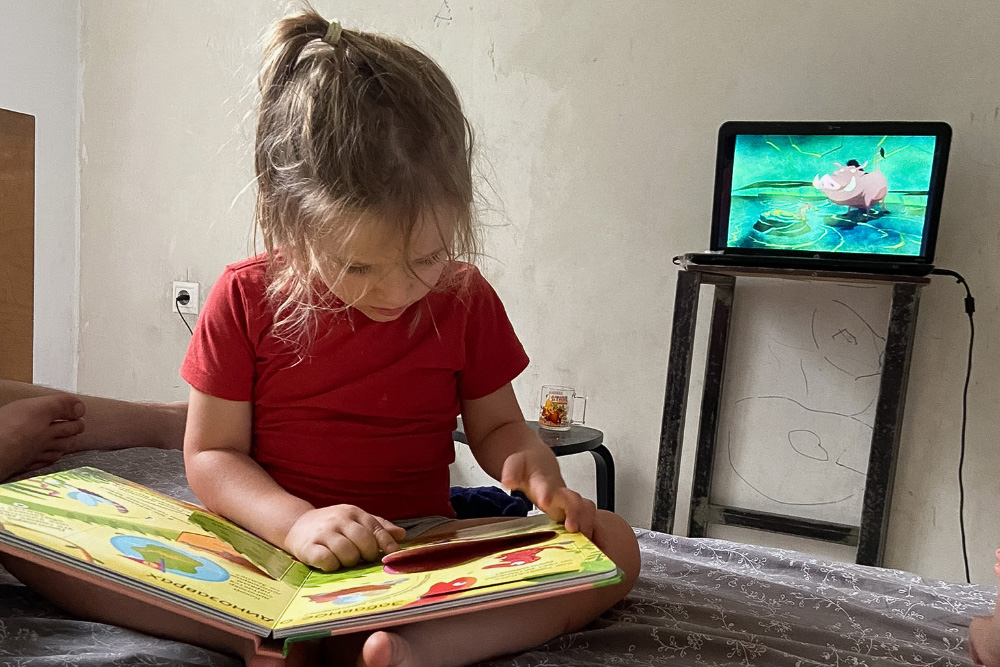 Книга с окошками легко занимает внимание дочери, даже если рядом играют мультики