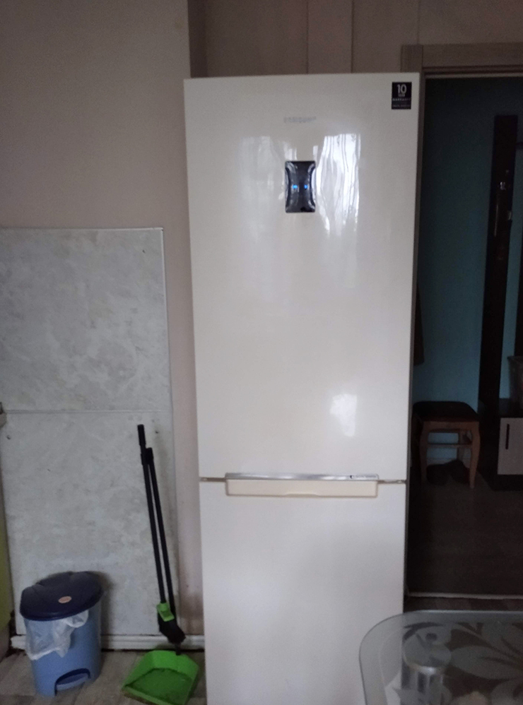 Холодильник наполовину задвинут в нишу на входе в кухню