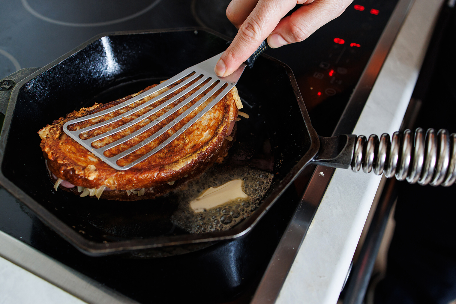 Шаг 4. Разогрейте сковороду, добавьте сливочное масло. Собранный сэндвич выложите на сковороду и прижмите рукой или лопаткой ко дну — так у тартина будет хрустящая румяная корочка. Иногда шеф прижимает крок⁠-⁠мадам второй тяжелой сковородкой