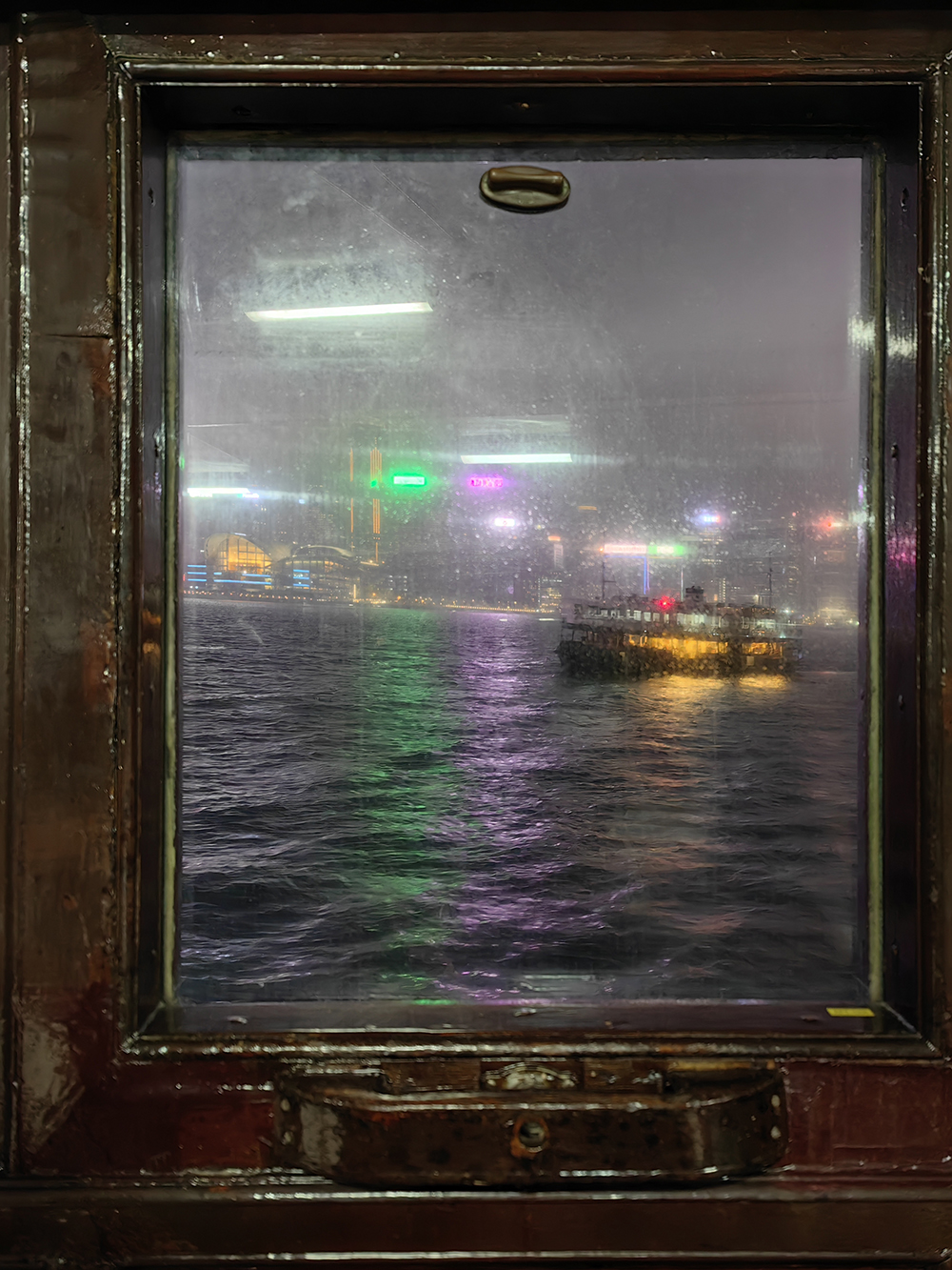 Вид из окна «Стар Ферри» — парома, который курсирует между полуостровом Коулун и островом Гонконг. Можно доехать на метро, но паром быстрее и дешевле, плюс дарит больше впечатлений, особенно во время вечернего светового шоу