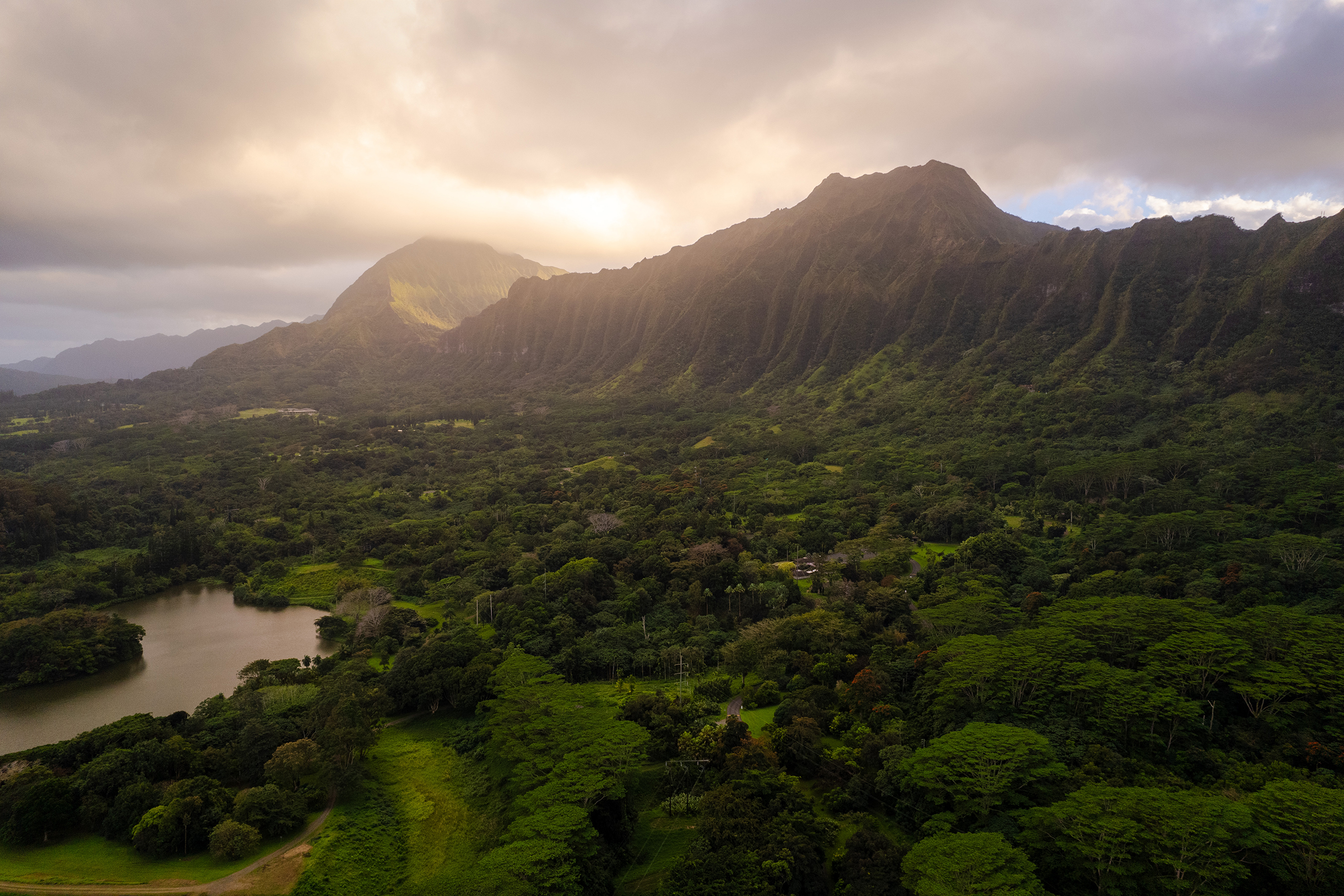 Закатное солнце скрывается за горным хребтом на Оаху. На Гавайях, если на одной стороне острова идет дождь, то на другой обязательно будет солнце. Здесь не бывает плохой погоды, а после дождя всегда будет радуга