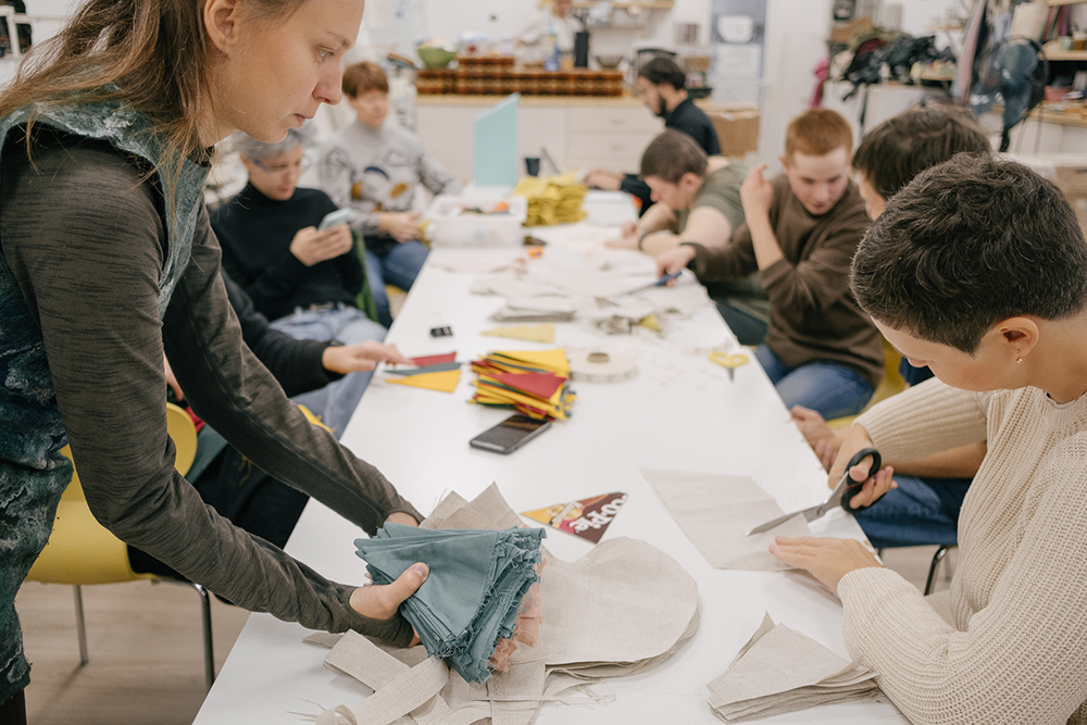 В швейной мастерской ребята занимаются раскройкой деталей, сшивают простые вещи. Сложными работами, например на машинке или глажкой утюгом, обычно занимаются педагоги
