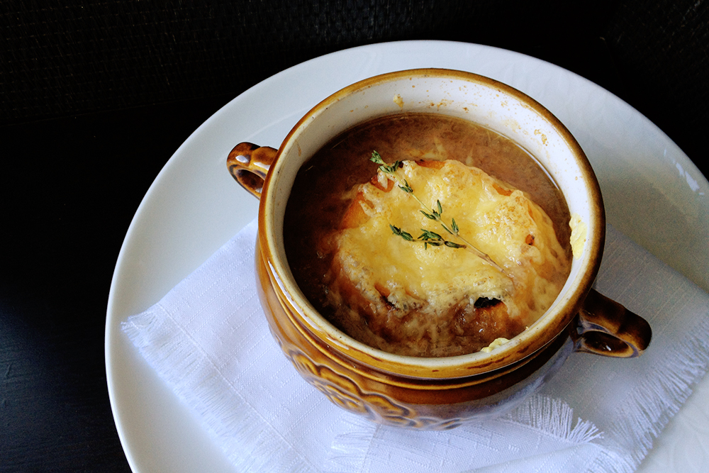 Блюда, приготовленные в горшочках, обычно подаются на тарелке. Но луковый суп — исключение: это запекаемый суп и его всегда подают в горшке. Более того, считается, что легкая неопрятность — бортики, испачканные луком и сыром, — придает ему особый шарм