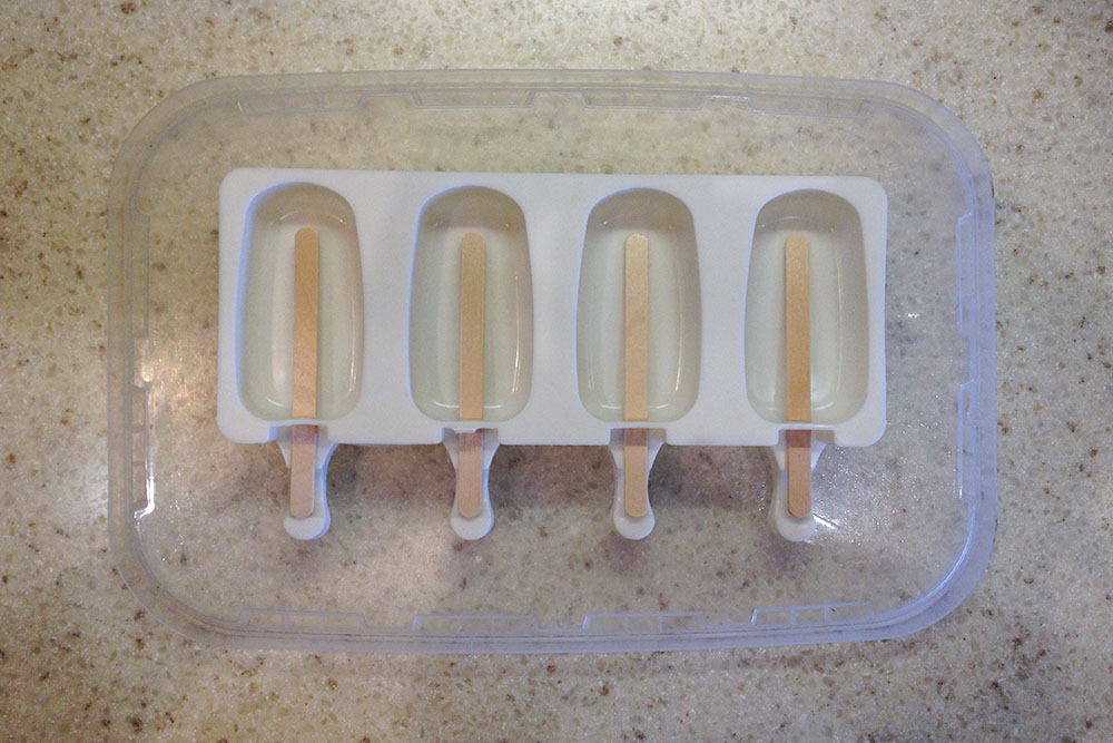 Пока работает мороженица, подготовьте формы: поставьте их на горизонтальную поверхность и вставьте палочки