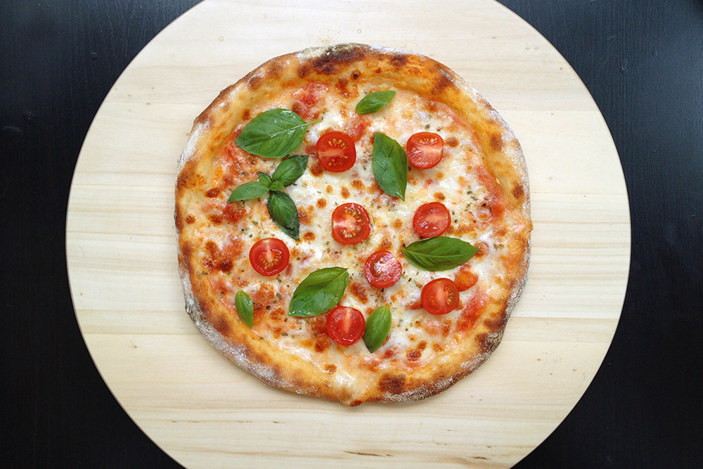 Горячую пиццу украсьте свежим базиликом и помидорами черри. Базилик можно использовать как фиолетовый, так и зеленый. Но мне нравится последний: на мой взгляд, так блюдо смотрится контрастнее и праздничнее