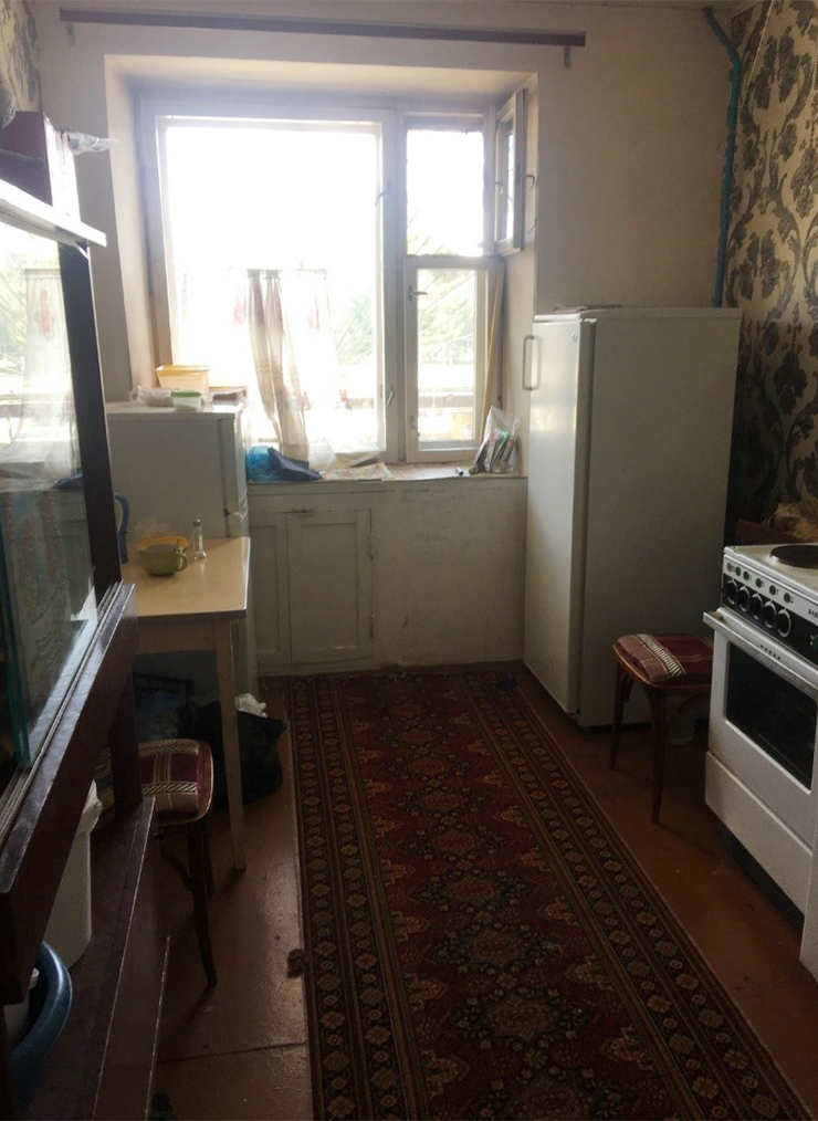 Состояние кухни: старый ковер, холодильник под окном, синие батареи, окрашенные еще в далеком 1990 году