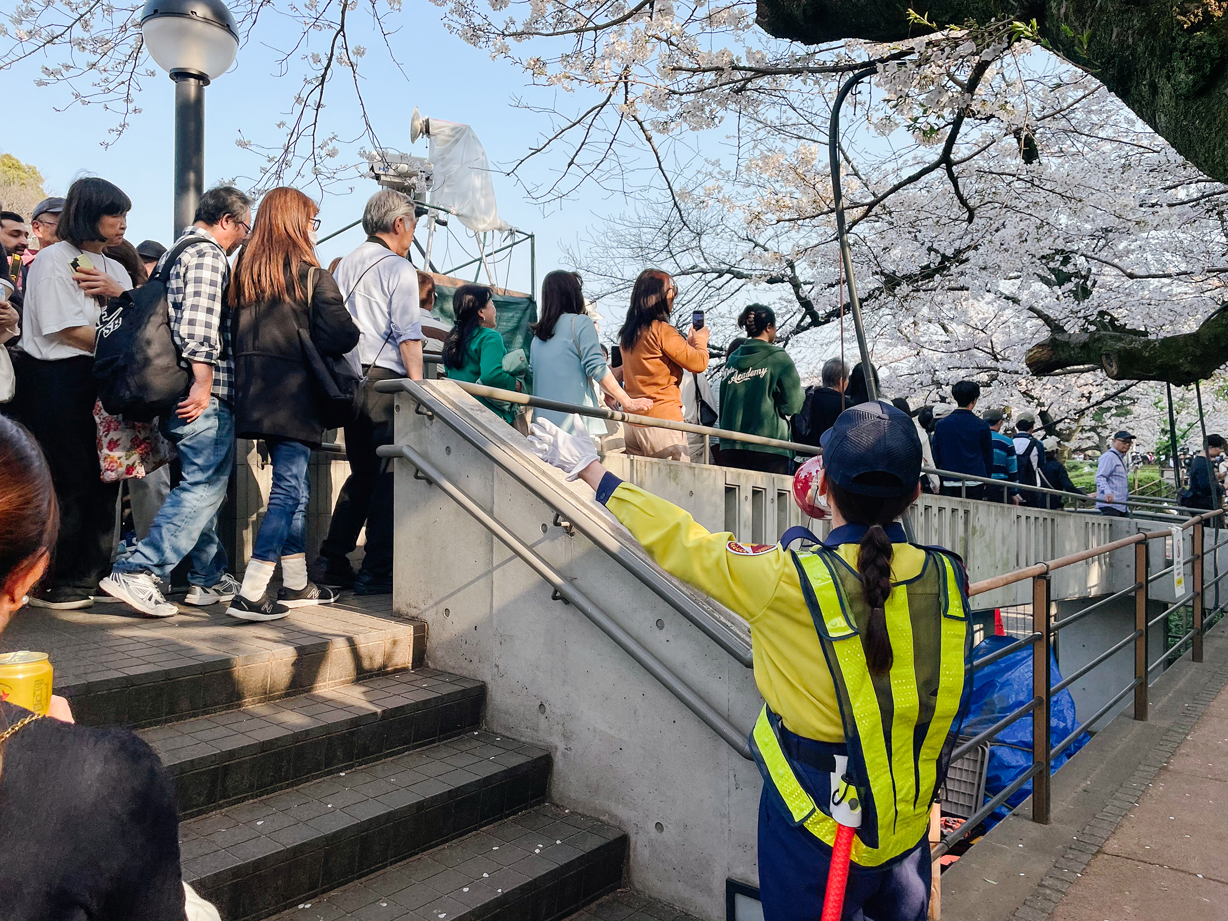 Сотрудница службы безопасности в громкоговоритель регулирует движение. Призывает людей не останавливаться и идти только вперед, не поворачивая назад