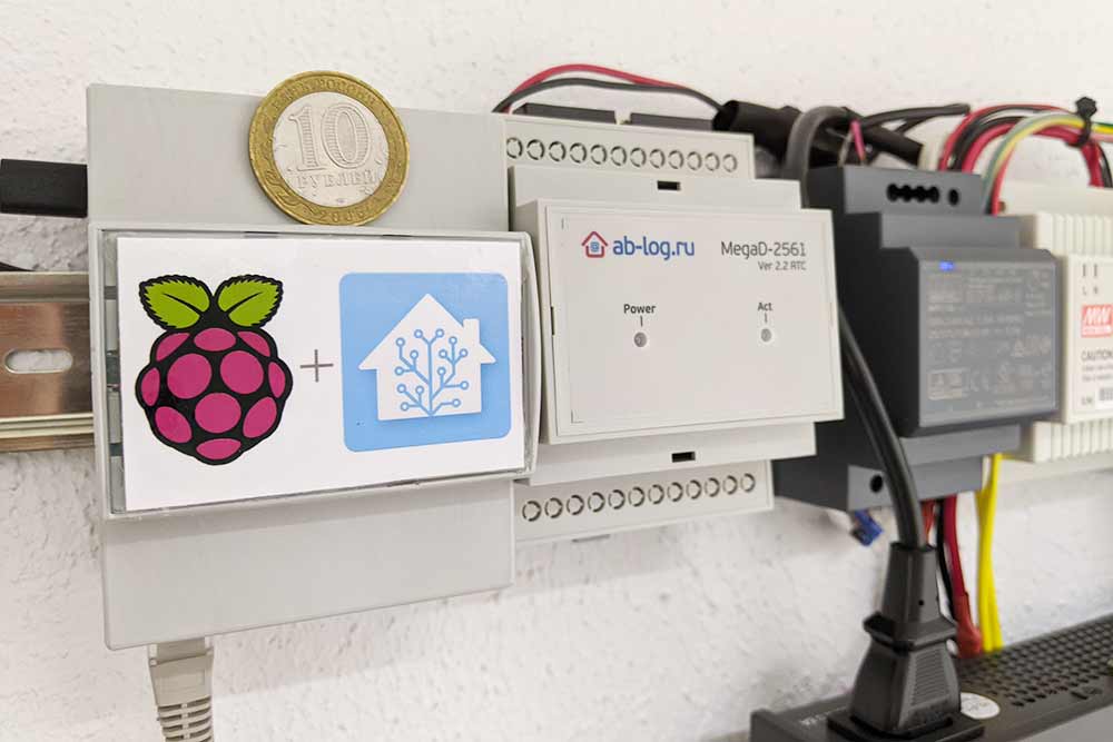 Raspberry Pi в корпусе, блок питания и другие устройства. Все закреплено на DIN⁠-⁠рейке. Синяя наклейка — логотип программной панели управления Home Assistant