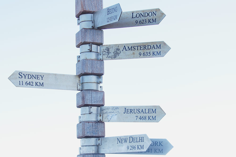 На вершине Кейп⁠-⁠пойнт у маяка — табличка, на которой указаны направление и расстояния до городов мира