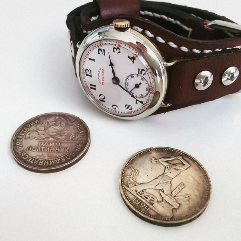 Часы марки «Гострест Точмех» 1920-х с механизмом «Юнитас 146», рядом серебряные монеты того же периода. Это часы станционных смотрителей на железной дороге, но в наручном, а не карманном исполнении
