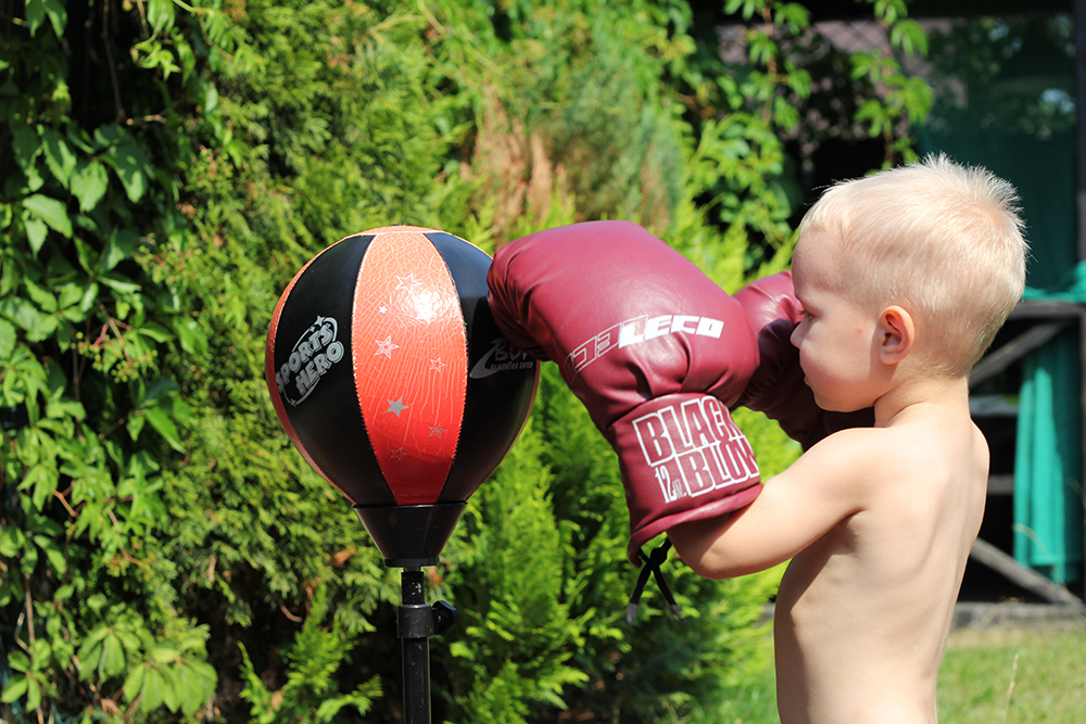 Сын тренирует удар на стационарной боксерской груше