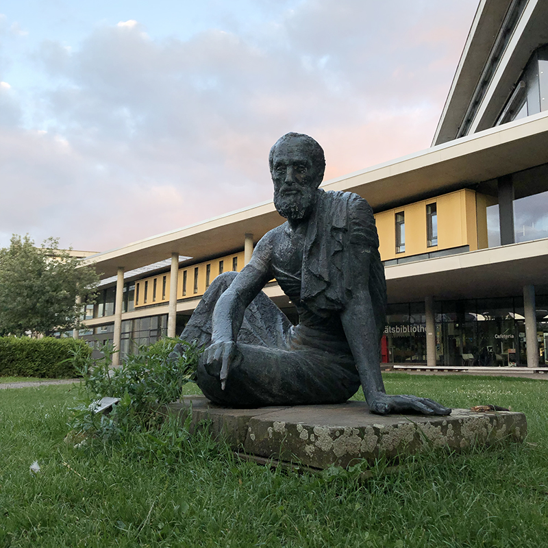 Статуя Архимеда на фоне университетской библиотеки