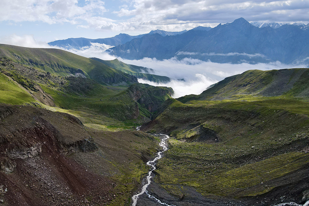 Потрясающий вид: вниз по ущелью стекает горная река, берущая начало на леднике Гергети