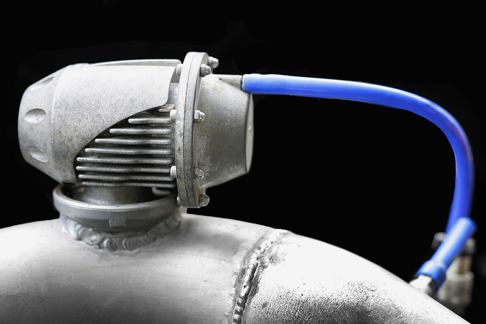 Блоу-офф на патрубке подвода сжатого воздуха, синий шланг подключен к нему же. Когда давление на впуске возрастает, давление через этот шланг передается на мембрану внутри редукционного клапана. Он открывается и стравливает избыточное давление наружу. Такие часто используют в автоспорте либо в тюнинге, чтобы получить от турбины «пшик». Источник: taro911_Photographer / Shutterstock