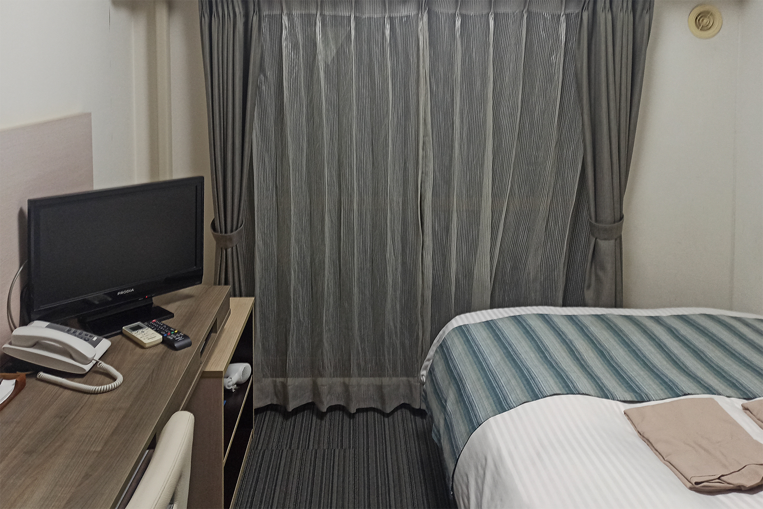 Комната в бизнес-отеле Mystays крошечная, но в ней поместились рабочий стол, стул и даже маленький телевизор. В нише под столом — холодильник. Номер уставший, зато жить здесь дешево