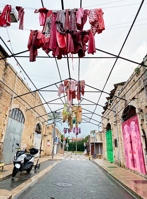 Улочка в старом районе Яффа, где одежда на перекладинах висит как арт⁠-⁠объект