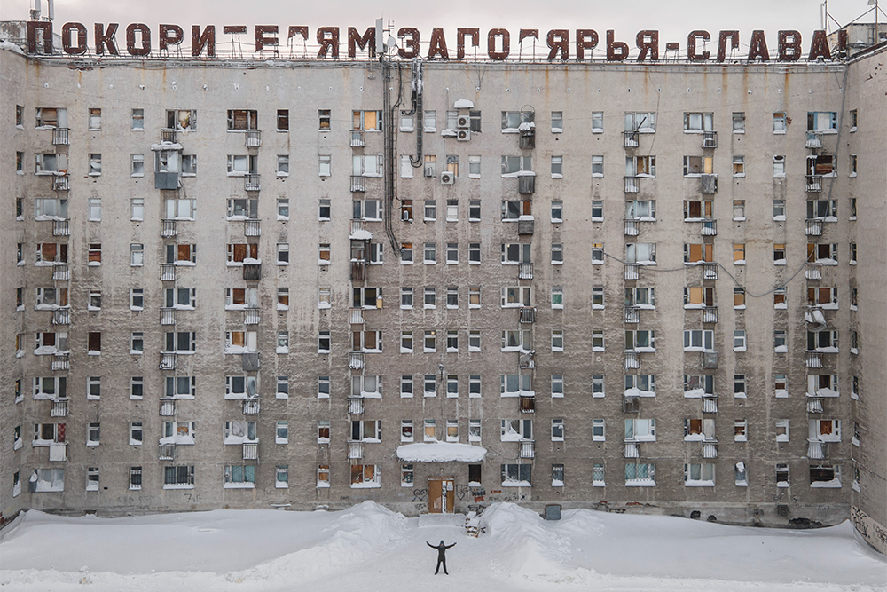 В Воркуте много старых советских вывесок-лозунгов. На фото я стою перед жилым домом. По забитым окнам видно, как много квартир покинуты