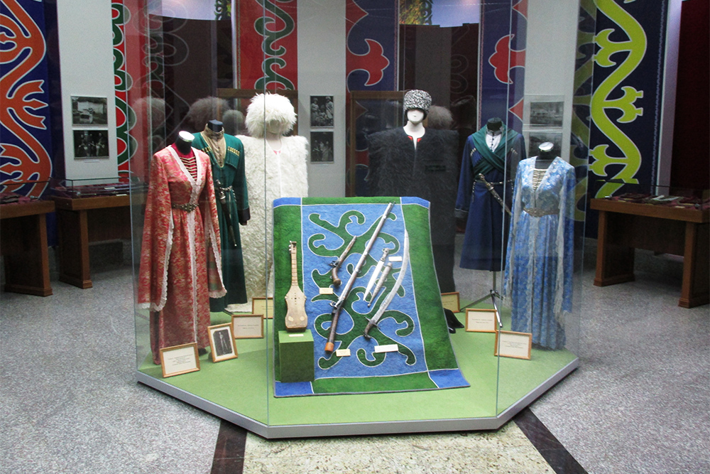 На фото экспонаты музея: национальная одежда и ковер ручной работы с чеченским орнаментом