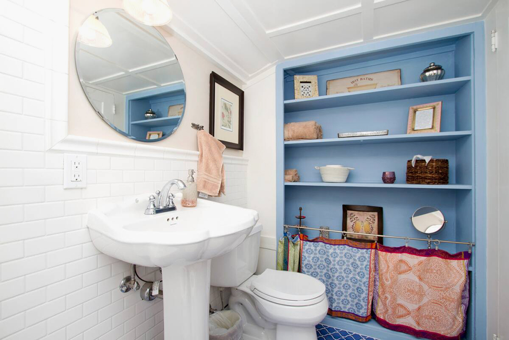 На стенах ванной комнаты белая плитка, а на полу — синяя марокканская