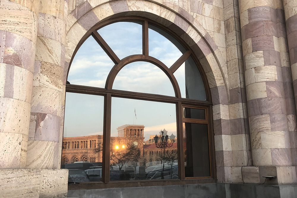 Отражение здания правительства в окне отеля Marriott на площади Республики