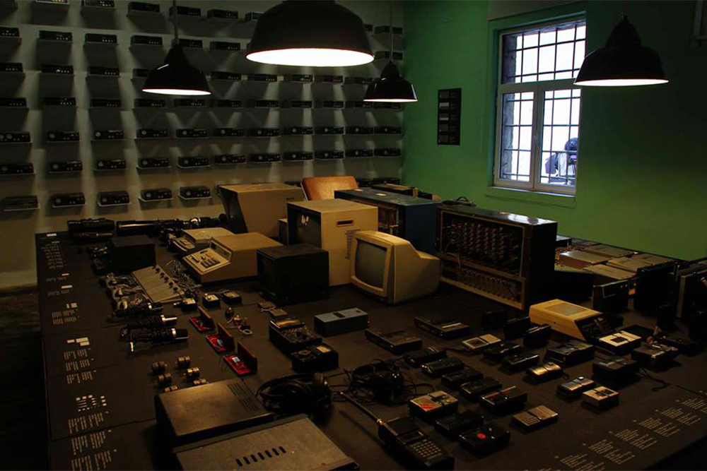На столе лежат диктофоны, устройства для видеонаблюдения и рации. Источник: muzeugjethi.gov.al