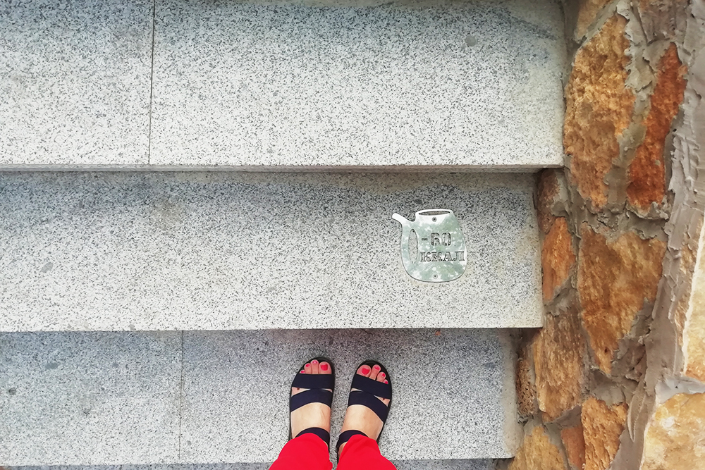 Каждая десятая ступень лестницы отмечена нарзанной кружкой с количеством потраченных на подъем калорий